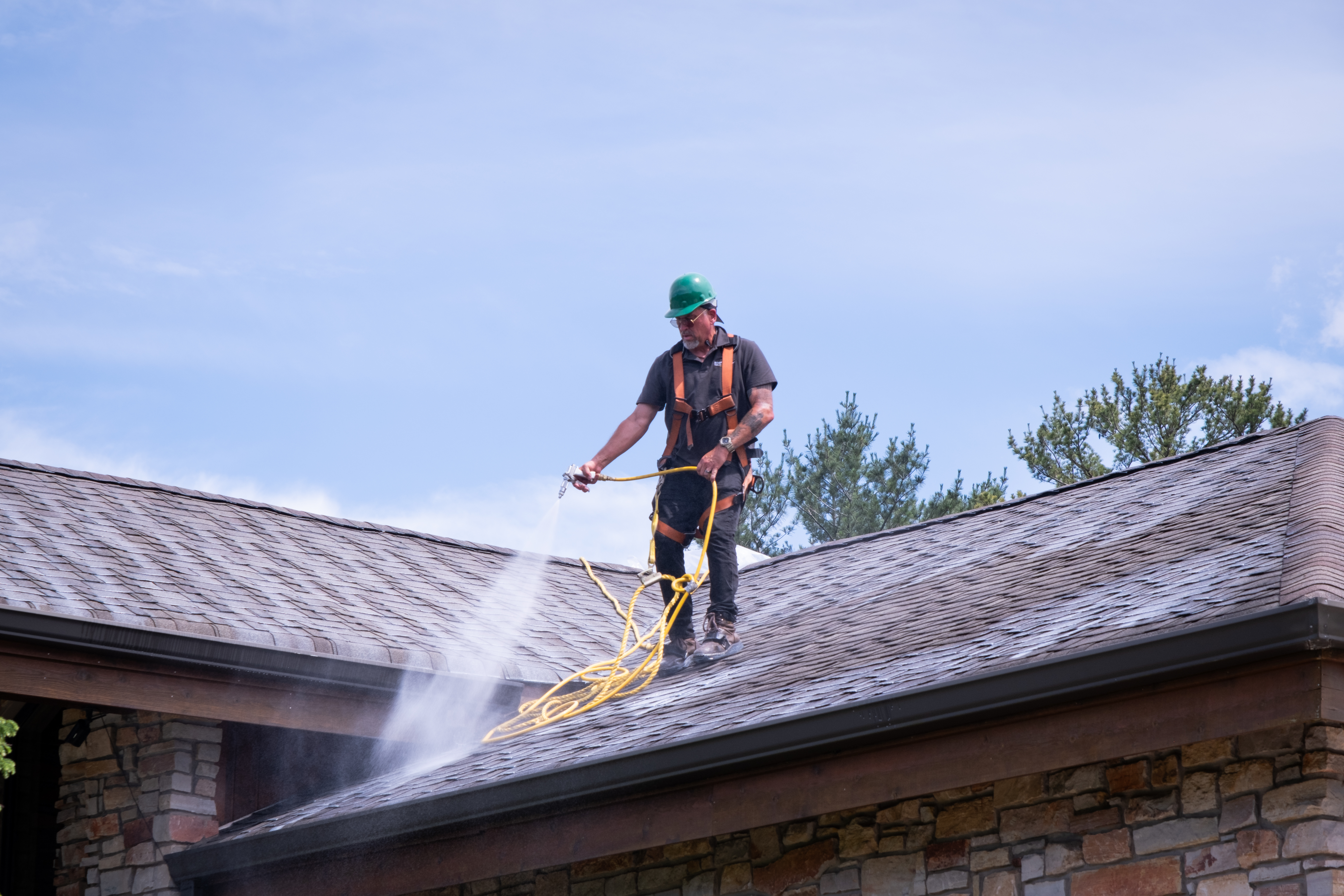Roof Maxx technician applying bio-oil treatment on a roof